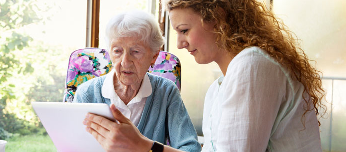 Family member showing a tablet to an elderly person